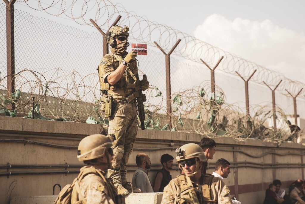A Danish coalition service member holds up a Danish flag to identify families during an evacuation at Hamid Karzai International Airport, Kabul, Afghanistan.