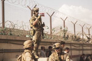 A Danish coalition service member holds up a Danish flag to identify families during an evacuation at Hamid Karzai International Airport, Kabul, Afghanistan.